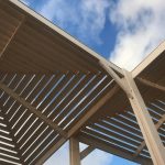 A low angle view of a wooden pergola with blue sky and white clouds in Haifa, Israel.