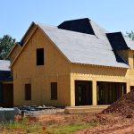 A partially built wooden house under construction, showcasing its progress and design in daylight.