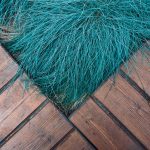 Colorful blue grass contrasting a rustic wooden deck in a diagonal composition.