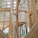 Interior view of wooden house frame under construction with visible scaffolding.